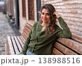 Smiling Woman Sitting on Wooden Bench Outdoors Casual Lifestyle Portrait 138988516
