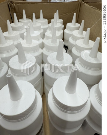 White squeeze bottles with nozzles arranged tightly in a cardboard box background White squeeze bottles with nozzles arranged tightly in a cardboard box background 138989656