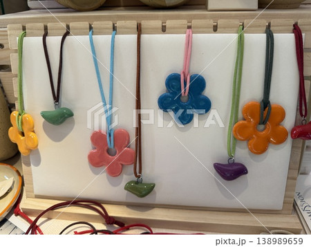 Ceramic necklaces displayed on white background, featuring colorful flower and leaf pendants 138989659