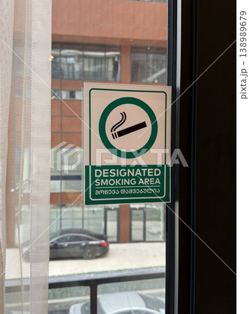 Designated smoking area sign on glass window with urban background view Designated smoking area sign on glass window with urban background view 138989679