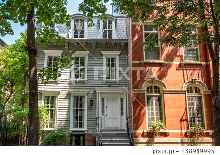 New york, usa august 15,2024. Historic townhouse architecture featuring contrasting facades, a red brick brownstone beside a light colored clapboard building on a sunny street New york, usa august 15,2024. Historic townhouse architecture featuring contrasting facades, a red brick brownstone beside a light colored clapboard building on a sunny street 138989995