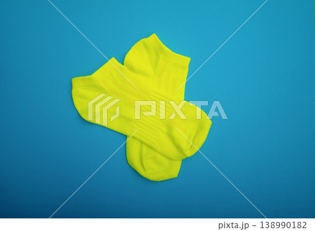 Neatly folded yellow socks on a blue background. A stylish sports accessory. Flat lay 138990182