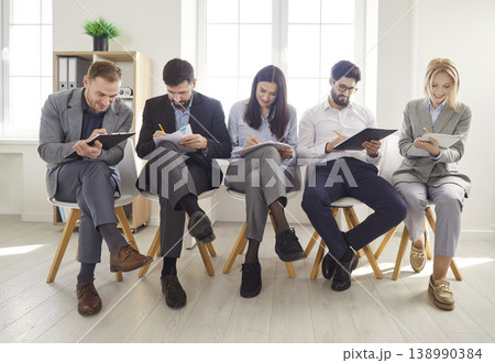 Diverse people on chairs in row waiting in queue for job interview turn in office, applicants Diverse people on chairs in row waiting in queue for job interview turn in office, applicants 138990384
