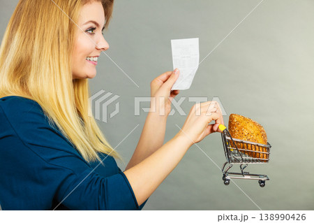Happy woman holding shopping basket with bread Happy woman holding shopping basket with bread 138990426