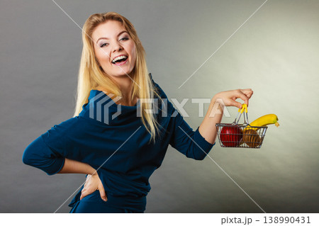 Woman holding shopping basket with fruits inside Woman holding shopping basket with fruits inside 138990431