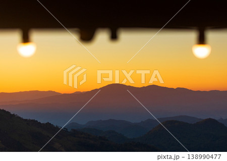 Golden hour mountain layers viewed through illuminated bulbs at dusk Golden hour mountain layers viewed through illuminated bulbs at dusk 138990477