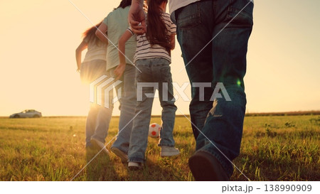 Parents run with child kid playing football green lawn, children kicking ball, mother father girl boy happy family sunset, community health concept: active family playing football outdoors at sunset Parents run with child kid playing football green lawn, children kicking ball, mother father girl boy happy family sunset, community health concept: active family playing football outdoors at sunset 138990909