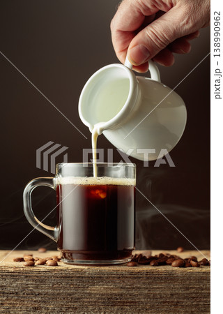 Coffee in a clear glass mug with cream being poured. Coffee in a clear glass mug with cream being poured. 138990962