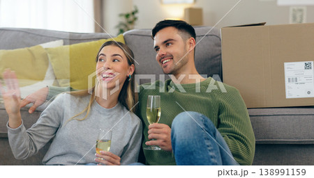 Happy couple, celebration and champagne for moving home or new property, drink in living room. Man, woman and wine glass for achievement in apartment boxes for change or floor chat, cheers at sofa Happy couple, celebration and champagne for moving home or new property, drink in living room. Man, woman and wine glass for achievement in apartment boxes for change or floor chat, cheers at sofa 138991159