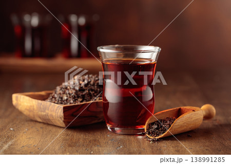 Glass transparent cup of black tea and dry tea in old wooden dish. 138991285