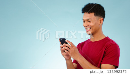 Man, smile and phone for social media in studio on blue background with mock up for announcement. Cape Town, male model and reading of notification, alert or offer on mobile app, website or internet 138992373