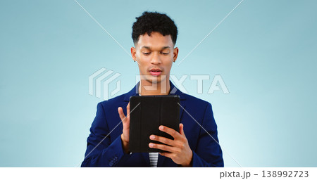 Man in studio, typing on tablet for business ideas and research for creative startup schedule. Thinking, agenda and professional person with digital app, scroll and social media on blue background. Man in studio, typing on tablet for business ideas and research for creative startup schedule. Thinking, agenda and professional person with digital app, scroll and social media on blue background. 138992723