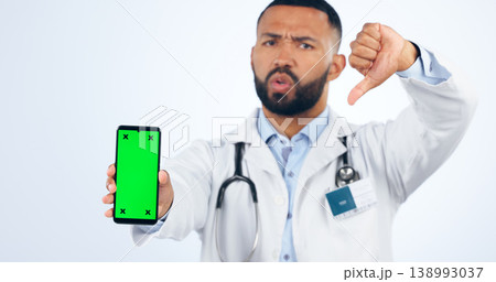 Phone, green screen and portrait of doctor with thumbs down, review or fake news in white background. Studio, healthcare or sign for negative, feedback and dislike mobile app for telehealth services Phone, green screen and portrait of doctor with thumbs down, review or fake news in white background. Studio, healthcare or sign for negative, feedback and dislike mobile app for telehealth services 138993037
