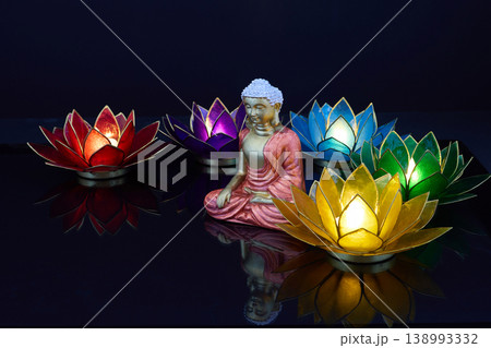 Vesak. Buddha statue meditating surrounded by glowing lotus candle holders 138993332