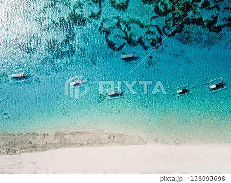 Drone view of turquoise ocean with traditional boats near white sandy beach in Bali Drone view of turquoise ocean with traditional boats near white sandy beach in Bali 138993698