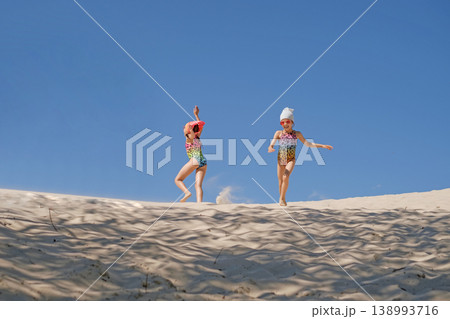 Funny girls in leopard print swimsuits have fun running and dancing on the sand by the sea Funny girls in leopard print swimsuits have fun running and dancing on the sand by the sea 138993716