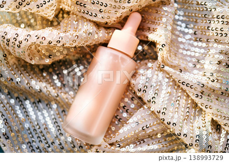 Cosmetic serum bottle on shimmering sequin fabric Cosmetic serum bottle on shimmering sequin fabric 138993729