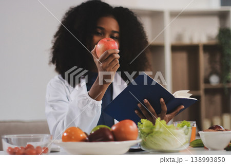 Young nutritionist showing bell peppers during an online video call consulting about healthy eating, sitting at home at a table with vegetables, laptop and measuring tape Young nutritionist showing bell peppers during an online video call consulting about healthy eating, sitting at home at a table with vegetables, laptop and measuring tape 138993850
