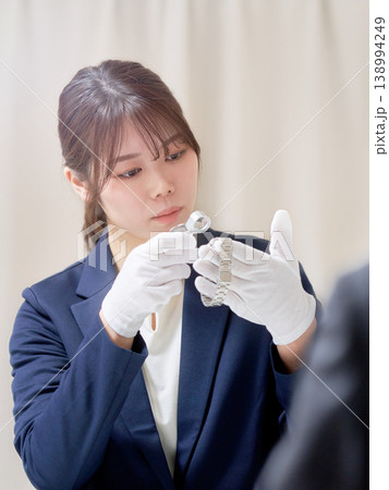 時計をルーペで確認する女性の鑑定士による買取査定 138994249