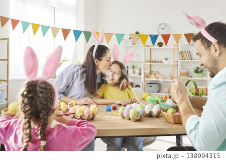 Happy family decorating for Easter, doing eggs ornaments on spring holiday tradition 138994315