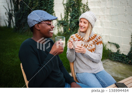 Diverse friends enjoying warm drinks and conversation outdoors Diverse friends enjoying warm drinks and conversation outdoors 138994484
