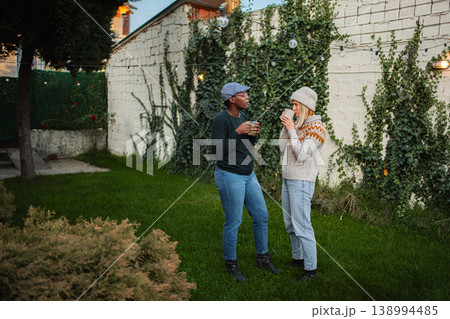 Diverse women friends enjoying conversation with coffee in backyard 138994485