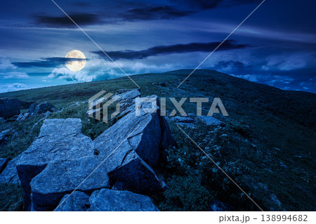 rocks and rolling hills in mountain landscape in summer at night. full moon over scenery with green grass on alpine meadow under dark sky with clouds. mysterious recreation tourism and wanderlust rocks and rolling hills in mountain landscape in summer at night. full moon over scenery with green grass on alpine meadow under dark sky with clouds. mysterious recreation tourism and wanderlust 138994682