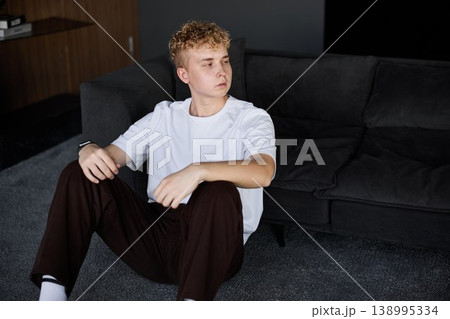 Casual relaxing pause. Young man ponders indoors peacefully Casual relaxing pause. Young man ponders indoors peacefully 138995334