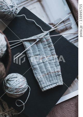 Hand knitted socks with needles and yarn ball in a basket. Concept for handmade and hygge slow life. Hand knitted socks with needles and yarn ball in a basket. Concept for handmade and hygge slow life. 138995755
