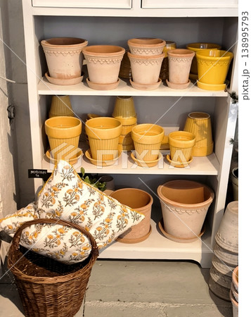 Ceramic flower pots and a decorative pillow on store shelves 138995793