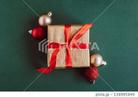 Gift box with red and golden balls on a green background. Holiday concept. Gift box with red and golden balls on a green background. Holiday concept. 138995849