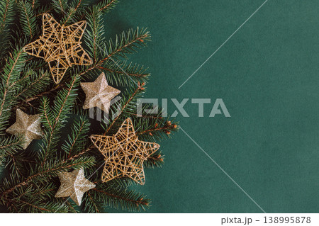 Spruce branches with golden sparkling stars on a dark green background. Spruce branches with golden sparkling stars on a dark green background. 138995878