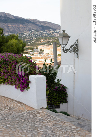 Picturesque Altea street view with vibrant purple bougainvillea, classic lamppost, and scenic mountain backdrop, ideal for Spanish holidays Picturesque Altea street view with vibrant purple bougainvillea, classic lamppost, and scenic mountain backdrop, ideal for Spanish holidays 138995952