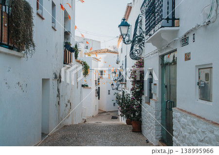 Exploring a charming narrow cobbled street in Altea Old Town Spain, adorned with whitewashed buildings and traditional lanterns, perfect for a memorable family holiday vacation Exploring a charming narrow cobbled street in Altea Old Town Spain, adorned with whitewashed buildings and traditional lanterns, perfect for a memorable family holiday vacation 138995966