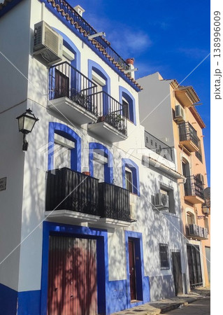 Traditional white and blue buildings with classic wrought iron balconies lining a sunny street in Altea, Spain, showcasing the city's unique architectural charm for memorable family holidays 138996009