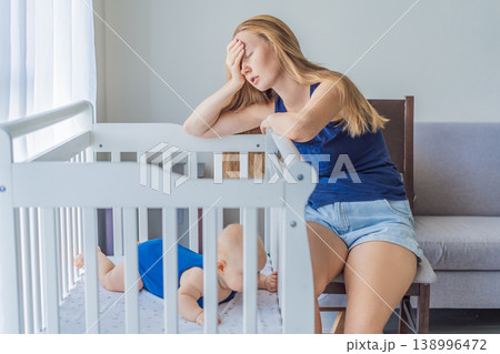 Very tired mother sitting by baby crib at home feeling exhausted. Sleep deprived mom caring for newborn at night. Parenting fatigue, motherhood stress, childcare and real family life concept Very tired mother sitting by baby crib at home feeling exhausted. Sleep deprived mom caring for newborn at night. Parenting fatigue, motherhood stress, childcare and real family life concept 138996472