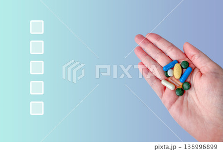 Hand with pills capsules vitamins supplements checklist on blue medical health background Hand with pills capsules vitamins supplements checklist on blue medical health background 138996899