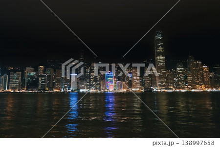 Hong Kong cityscape glows brightly at night over Victoria Harbour, displaying many tall buildings and water reflections Hong Kong cityscape glows brightly at night over Victoria Harbour, displaying many tall buildings and water reflections 138997658