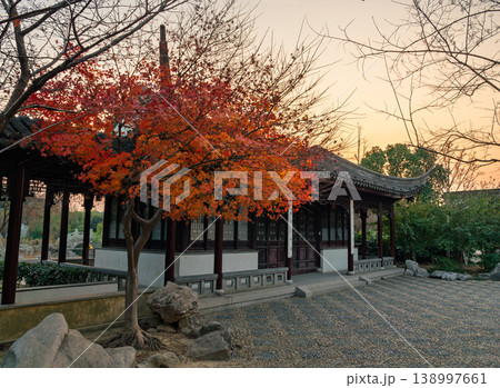 A traditional Chinese pavilion with a curved roof stands amidst vibrant red and orange maple trees in a peaceful classical garden. A traditional Chinese pavilion with a curved roof stands amidst vibrant red and orange maple trees in a peaceful classical garden. 138997661