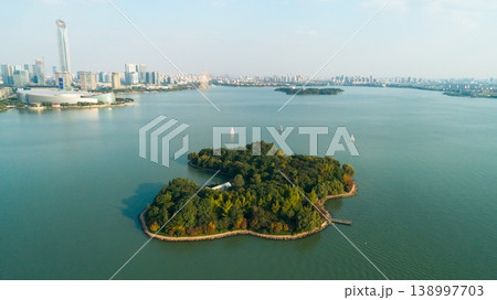 Expansive Jinji Lake in Suzhou with a verdant island, graceful sailboats, and modern city architecture 138997703