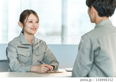 会議室でミーティング,打ち合わせをする作業着姿の製造業,工場勤務の男女スタッフ 会議室でミーティング,打ち合わせをする作業着姿の製造業,工場勤務の男女スタッフ 138998152