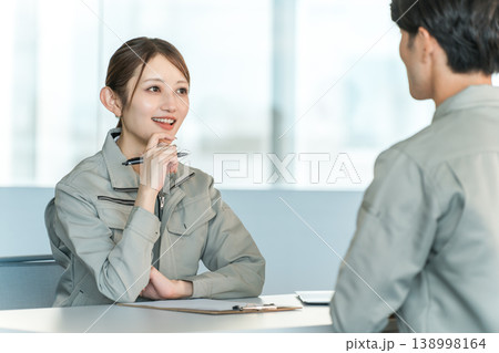 会議室でミーティング,打ち合わせをする作業着姿の製造業,工場勤務の男女スタッフ 会議室でミーティング,打ち合わせをする作業着姿の製造業,工場勤務の男女スタッフ 138998164