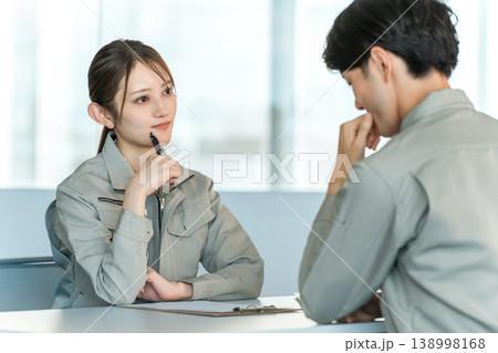 会議室でミーティング,打ち合わせをする作業着姿の製造業,工場勤務の男女スタッフ 138998168