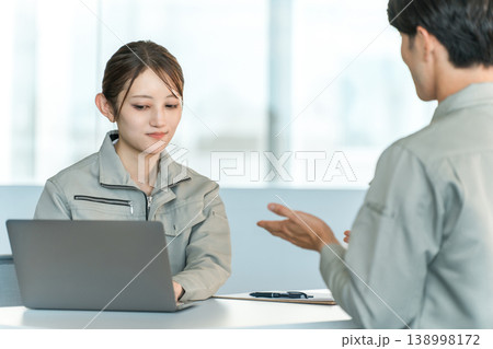 会議室でミーティング,打ち合わせをする作業着姿の製造業,工場勤務の男女スタッフ 138998172