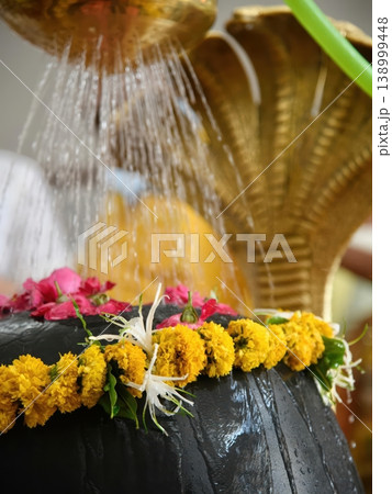 Sacred Hindu Ritual Abhishekam of Shiva Lingam with Water and Fresh Flower Offerings Sacred Hindu Ritual Abhishekam of Shiva Lingam with Water and Fresh Flower Offerings 138999448