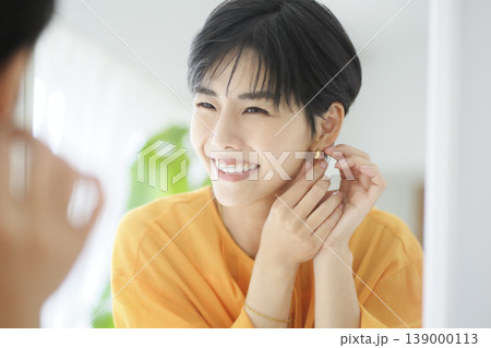 笑顔でイヤリングをつける女性 明るい表情 美容と日常イメージ 笑顔でイヤリングをつける女性 明るい表情 美容と日常イメージ 139000113