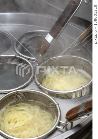 ラーメン店の厨房設備・ゆで麺機で麺を茹でる調理シーン 139001219