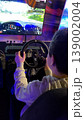 Teenager playing a car driving simulator in an arcade. 139002004