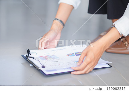 Hands arranging summary reports on a clipboard with charts and graphs in a clean office space. Business documentation, data presentation, paperwork management, and financial planning concept. 139002215