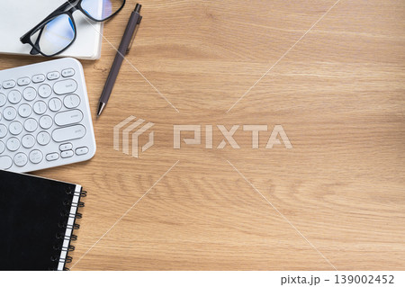 Elegant Workspace with Computer Keyboard, Notebook, Pen, Glasses, and Laptop on Light Wooden Desk for Creative or Office Use Elegant Workspace with Computer Keyboard, Notebook, Pen, Glasses, and Laptop on Light Wooden Desk for Creative or Office Use 139002452